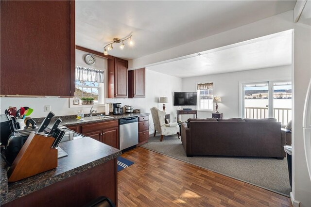 kitchen featuring dishwasher, dark countertops, dark wood-style floors, open floor plan, and a sink