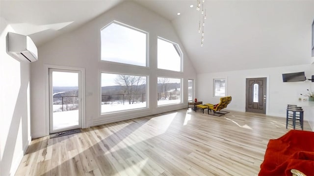 unfurnished living room with high vaulted ceiling, light wood finished floors, and a wall mounted AC