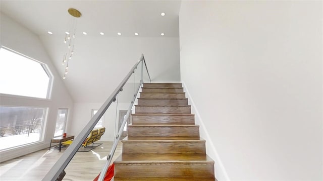 stairs featuring a towering ceiling, wood finished floors, and recessed lighting