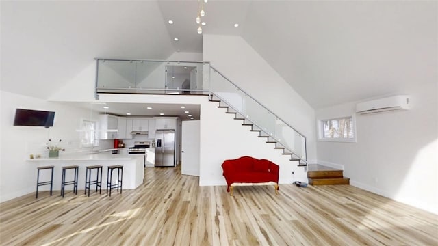 interior space featuring light wood finished floors, a wall unit AC, stairway, high vaulted ceiling, and recessed lighting