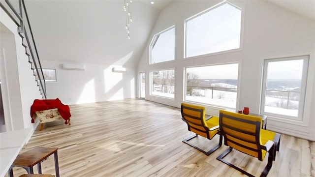 sitting room with high vaulted ceiling, light wood-type flooring, and a wall unit AC