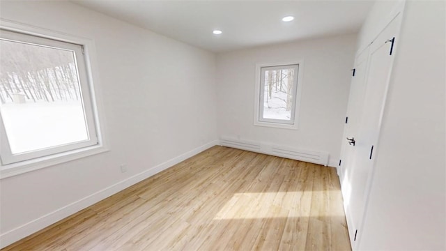 spare room with light wood-style floors, a baseboard radiator, baseboards, and recessed lighting