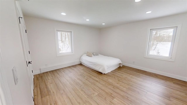 unfurnished bedroom with light wood finished floors, multiple windows, baseboards, and recessed lighting