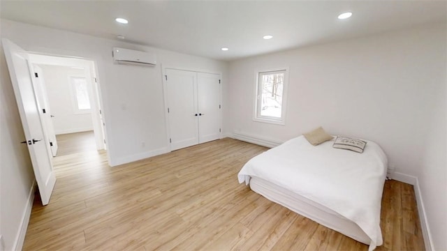 bedroom featuring light wood-style flooring, recessed lighting, baseboards, a wall mounted AC, and baseboard heating