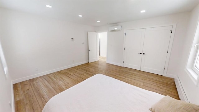 bedroom with light wood finished floors, a wall mounted air conditioner, and recessed lighting