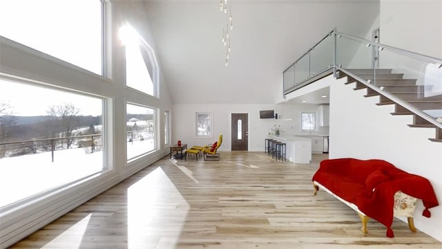 living area featuring plenty of natural light, stairs, a high ceiling, and light wood-style flooring