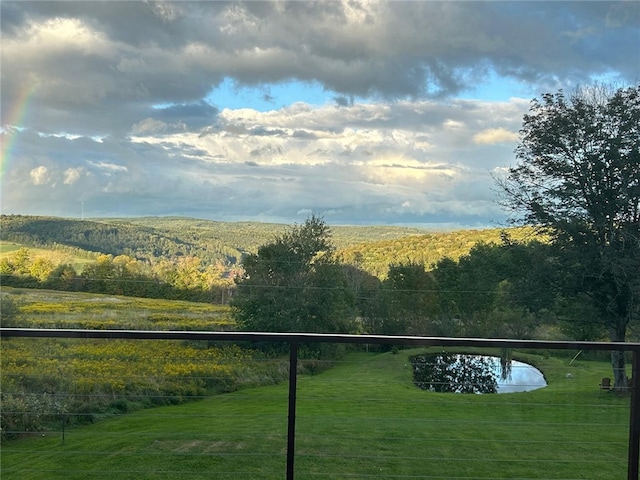 exterior space with a lawn, a water view, and a wooded view