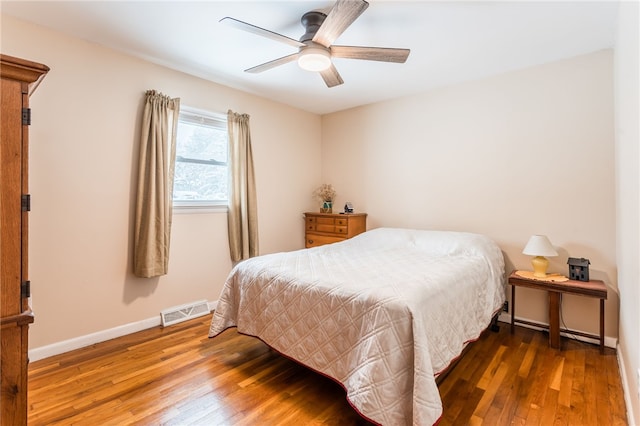 bedroom with ceiling fan, hardwood / wood-style floors, visible vents, and baseboards