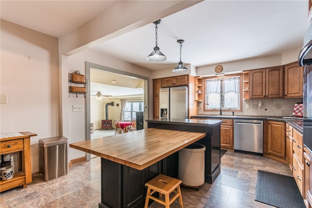 kitchen featuring wood counters, appliances with stainless steel finishes, a center island, a wood stove, and open shelves