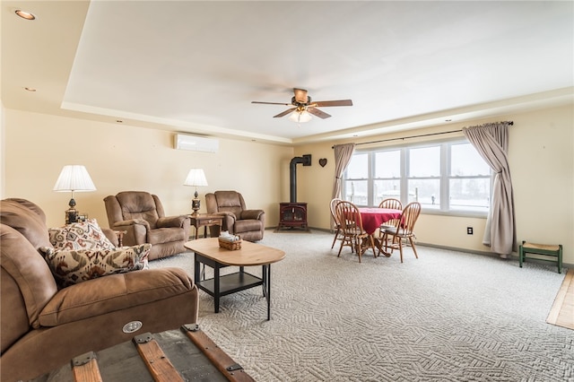 living area with ceiling fan, baseboards, an AC wall unit, carpet, and a wood stove