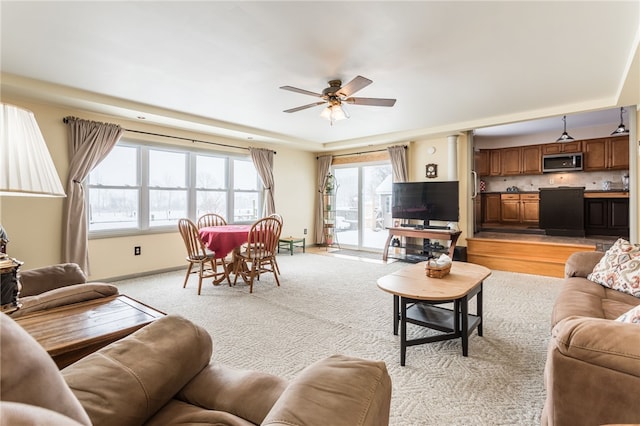 living room featuring ceiling fan, baseboards, and light colored carpet