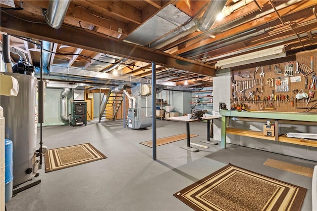 unfinished basement with heating unit, stairs, gas water heater, and a workshop area