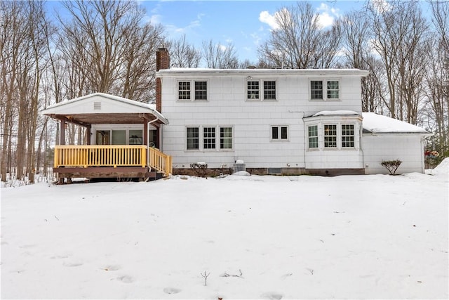 snow covered rear of property featuring a chimney