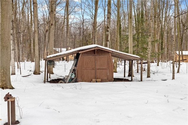 snow covered structure with an outdoor structure and a shed