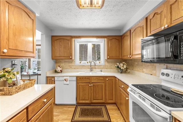 kitchen featuring light countertops, white appliances, a sink, and light wood-style flooring