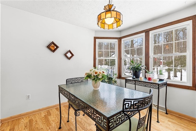 dining area featuring a textured ceiling, baseboards, and wood finished floors