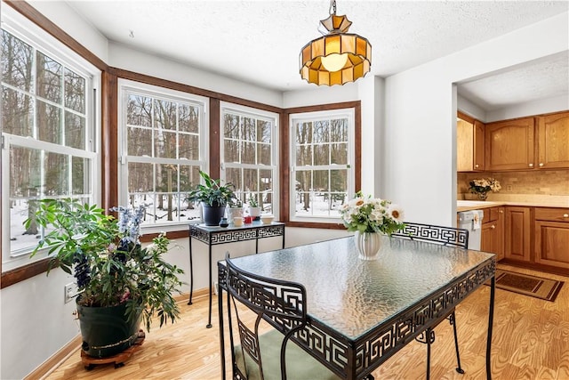 dining room with a textured ceiling, light wood finished floors, and baseboards