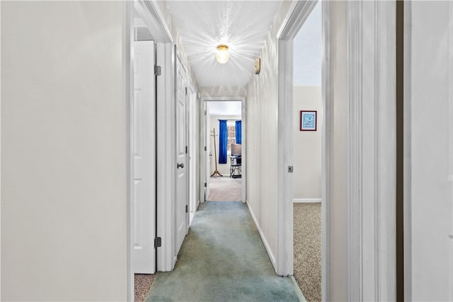 corridor with baseboards and carpet flooring