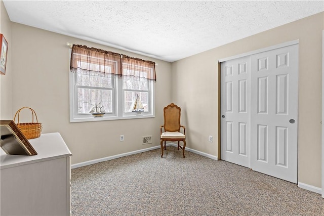 sitting room with a textured ceiling, baseboards, and carpet flooring