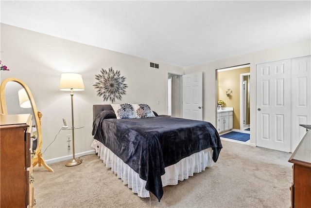 bedroom featuring baseboards, ensuite bathroom, visible vents, and light colored carpet