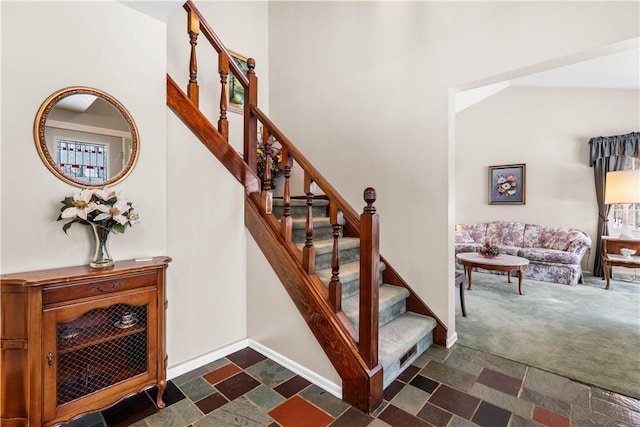 stairway featuring a high ceiling, carpet flooring, and baseboards