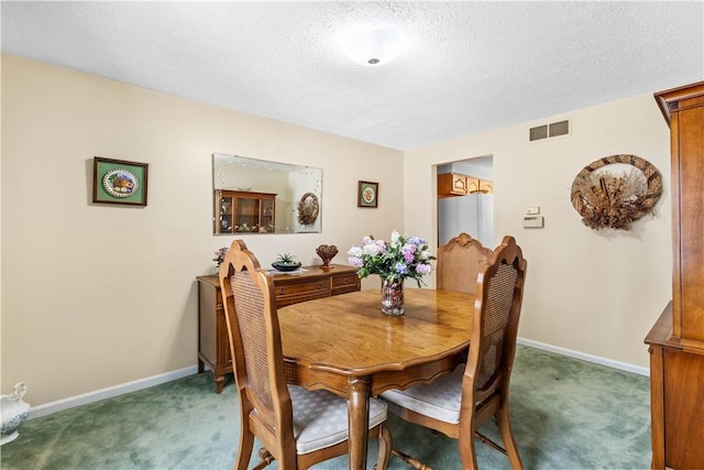 carpeted dining room with baseboards, visible vents, and a textured ceiling