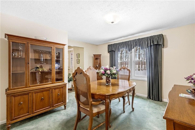 dining space with a textured ceiling, carpet floors, and baseboards