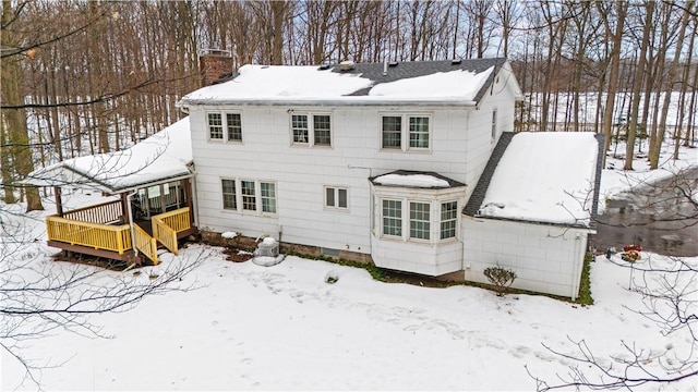 snow covered property featuring a chimney and a deck