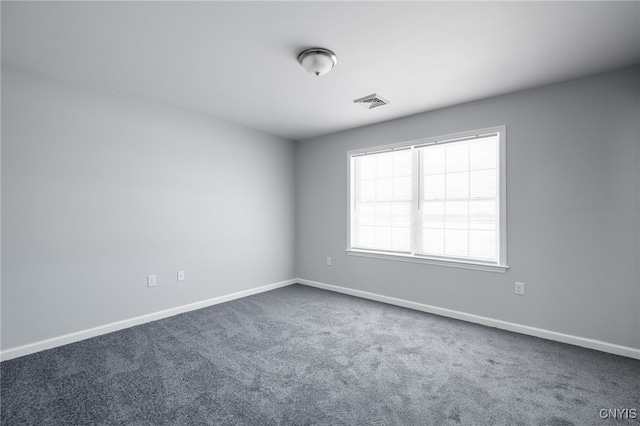 unfurnished room featuring visible vents, baseboards, and dark colored carpet