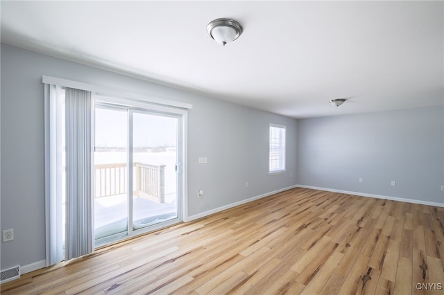 spare room with baseboards, visible vents, and light wood finished floors