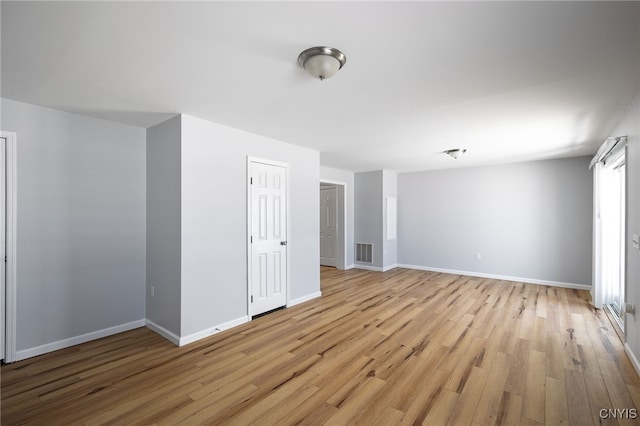 empty room with light wood-type flooring, visible vents, and baseboards