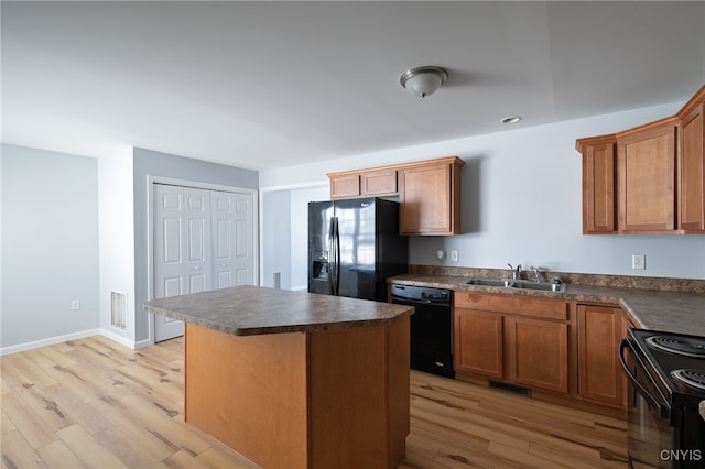 kitchen featuring a sink, visible vents, light wood-style floors, black appliances, and dark countertops