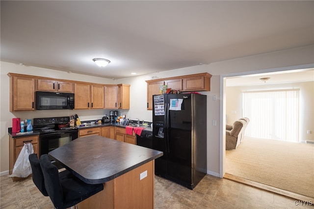 kitchen with dark countertops, a kitchen island, black appliances, a kitchen bar, and a sink