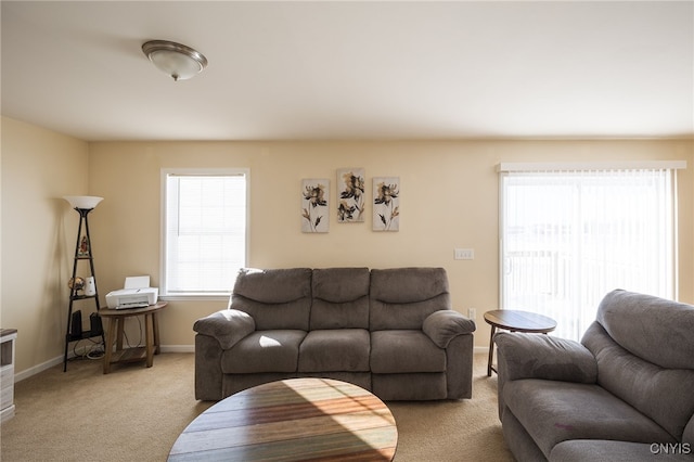 living area with baseboards and light colored carpet