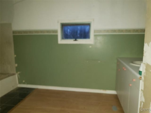 clothes washing area with baseboards and wood finished floors