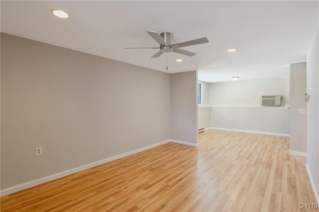 spare room featuring a wall mounted AC, recessed lighting, light wood-style flooring, and baseboards