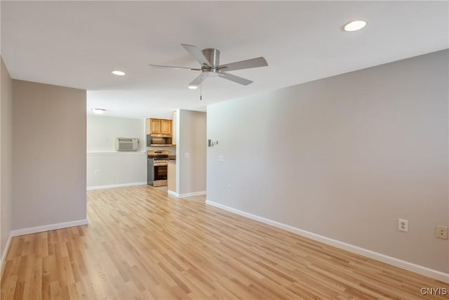 empty room with light wood-type flooring, a wall mounted air conditioner, and baseboards