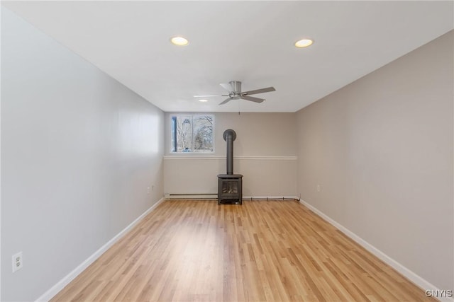 unfurnished living room with light wood finished floors, a wood stove, and baseboards