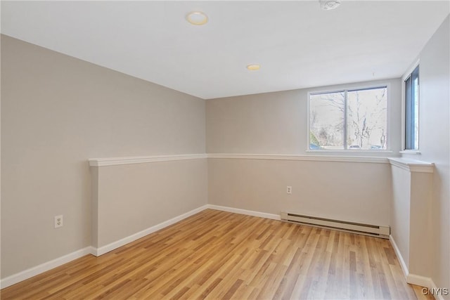 spare room featuring light wood-style flooring, a baseboard heating unit, and baseboards