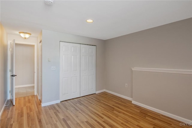 unfurnished bedroom with light wood-style floors, baseboards, a closet, and recessed lighting