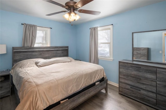 bedroom featuring multiple windows, ceiling fan, baseboards, and wood finished floors