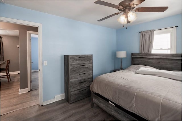 bedroom featuring ceiling fan, visible vents, baseboards, and wood finished floors