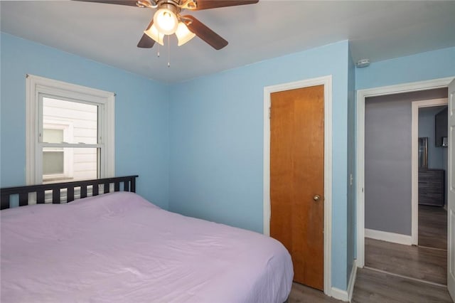 bedroom with a ceiling fan, baseboards, and wood finished floors