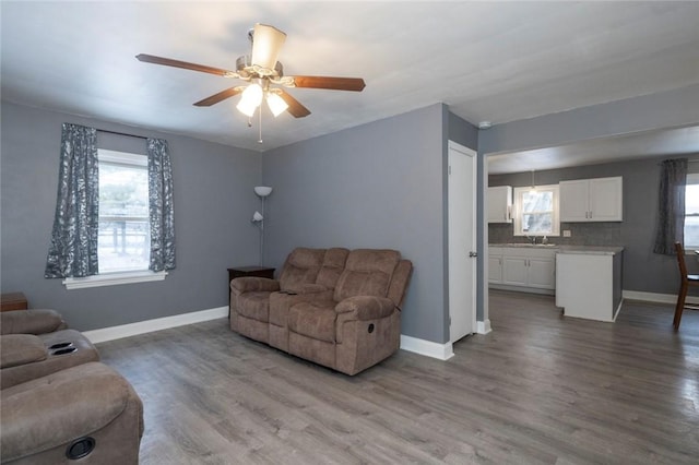 living room featuring ceiling fan, baseboards, and wood finished floors