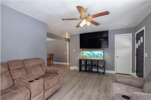 living area featuring ceiling fan, baseboards, and wood finished floors