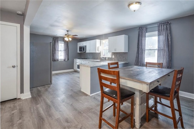 dining space featuring ceiling fan, baseboards, and wood finished floors