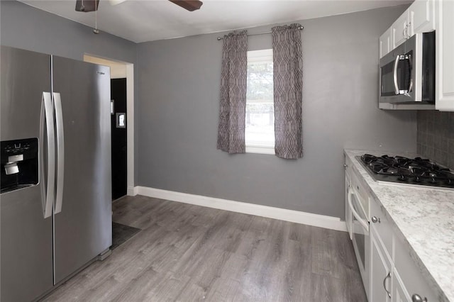 kitchen featuring white cabinetry, light wood-style floors, light countertops, appliances with stainless steel finishes, and tasteful backsplash