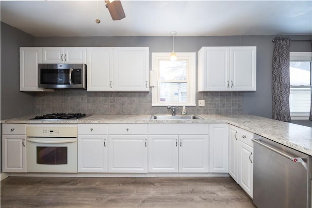 kitchen with stainless steel appliances, light countertops, white cabinets, and a sink