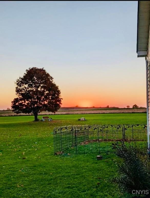 yard at dusk featuring a rural view