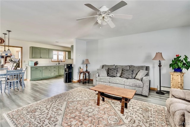 living room with ceiling fan, a baseboard radiator, light wood-style flooring, and baseboards